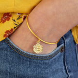 Image shows model wearing gold textured hexagon initial bangle bracelet with the initial E