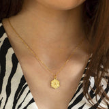 Image shows model wearing gold textured hexagon initial necklace with initial A