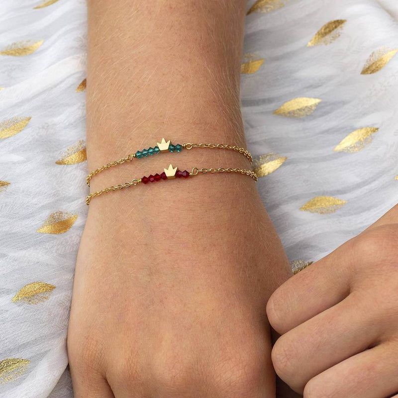 Image shows model wearing two  tiny gold crown birthstone bar bracelets December and July birthstones