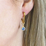 Image shows model wearing Triangle Huggie Earrings with Birthstone Detail