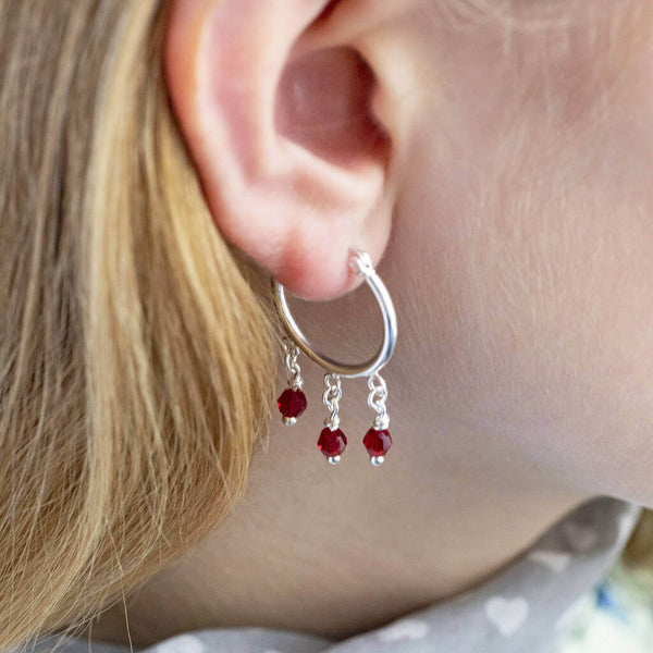 Image shows model wearing silver Triple Birthstone Huggie Hoop Earrings with July birthstone