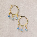 Image shows gold Triple Birthstone Huggie Hoop Earrings with March birthstone