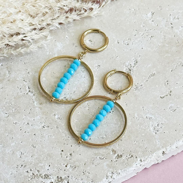 Image shows Turquoise Beaded Stack Crystal Earrings lying on a stone slab
