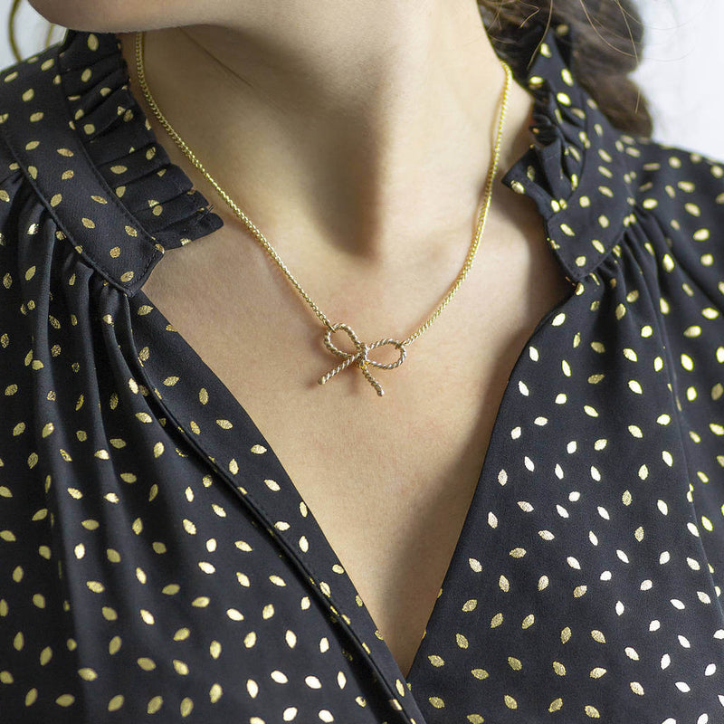 Image shows model wearing gold Twisted Bow Knot Necklace