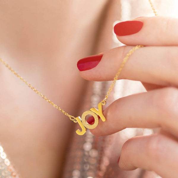 Image shows model holding gold Wear It With JOY Necklace