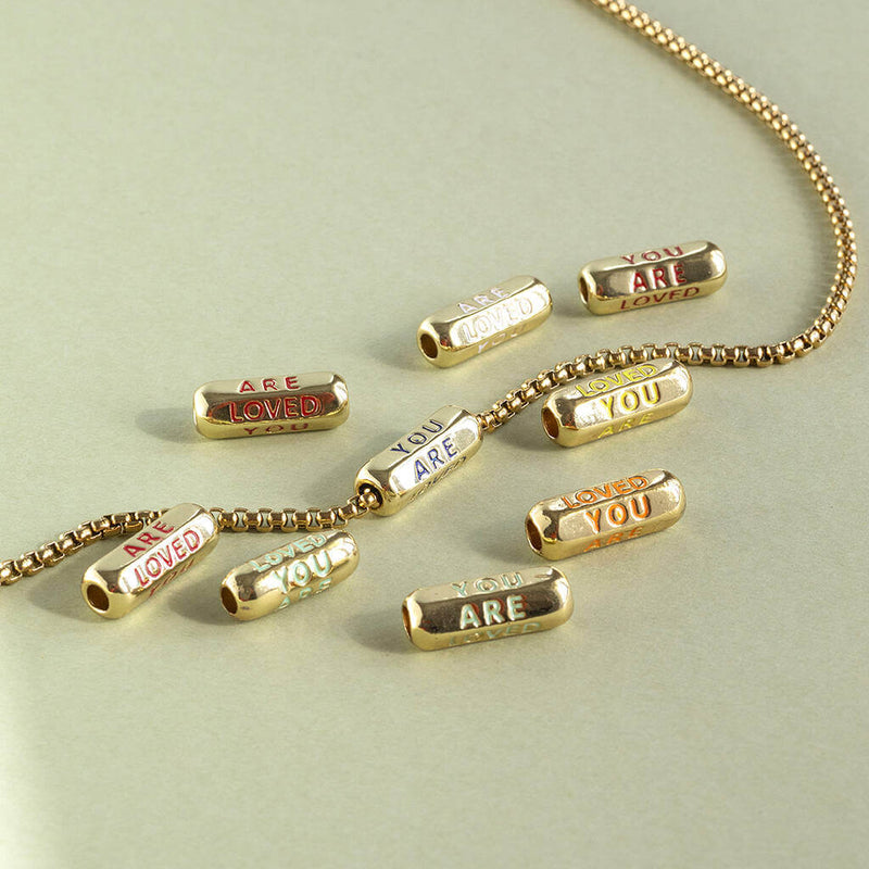 Image shows gold necklace with you are loved bead detail
