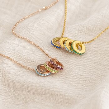 Colourful birthstone ring necklaces in gold and rose gold, featuring stacked crystal ring charms