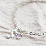 Silver initial charm bracelet with a pink birthstone crystal, timeless personalised jewellery for stacking and styling.