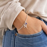 Silver initial charm bracelet with a purple birthstone crystal, delicate personalised jewellery for everyday layering.