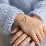 Rose gold friendship knot bangle styled with an initial and birthstone charm, elegant everyday stacking jewellery.