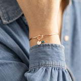 Rose gold friendship knot bangle with initial and birthstone charms, delicate stacking jewellery for everyday style.