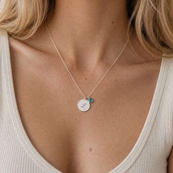 Silver plated initial disc necklace styled with a teal birthstone charm for a colourful everyday layered jewellery look