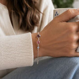Silver birthstone bracelet with pink, lilac and burgundy crystals styled in a cosy everyday look