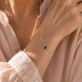 Silver birthstone bracelet styled with a pink blouse, featuring three colourful crystal birthstones