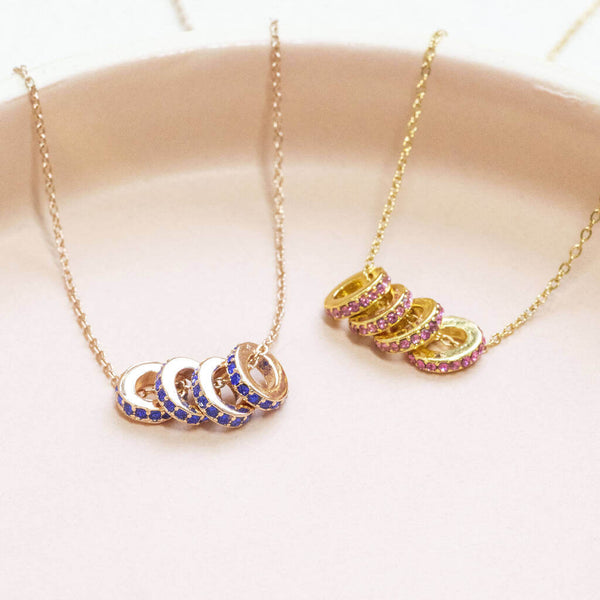 Image shows two 40th Birthday Birthstone Rings Necklaces from left to right: Rose gold necklace with September Sapphire birthstone and gold necklace with October Rose Birthstone.