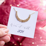 Gold crescent moon necklace presented on a Wear it with JOY sentiment card.