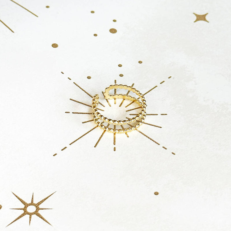 Image shows an adjustable gold plated double band ring on a white and gold starry background