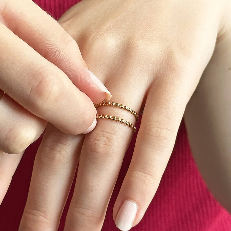 Image shows model wearings a dotted double band ring in gold plated stainless steel