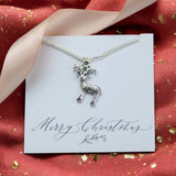 image shows a silver plated reindeer necklace presented on a Merry Christmas sentiment card on a red background with gold sparkle