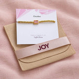 October pink baguette birthstone bracelet presented on its meaning card with branded JOY suedette gift pouch.