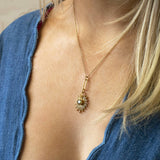 Image shows model in scalloped denim top wearing a heart starburst necklace with perodot august birthstone