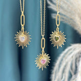 Image shows three Birthstone Heart Starburst Necklaces in front of a green backdrop. From left to right: April crystal, October Rose and August Peridot.