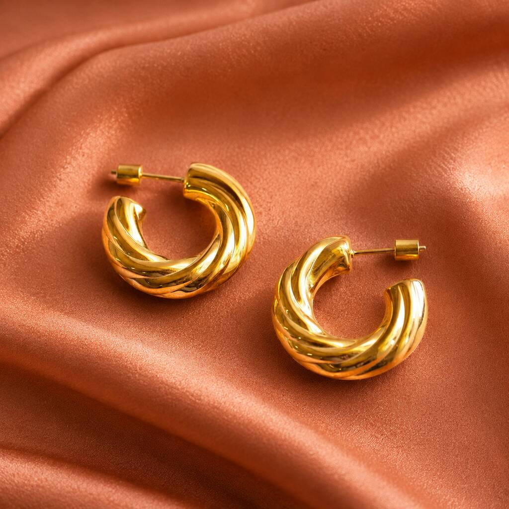 Textured gold hoop earrings with a twisted rope design and polished finish, styled on satin fabric for a luxe look