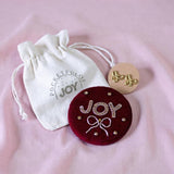 Bow gift set with velvet compact mirror embroidered with a bow detail and the word JOY, gold bow stud earrings and cotton pouch