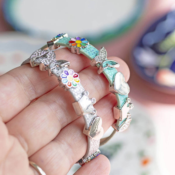 A silver and a green faux leather buckle bracelet with sparkly heart, sparkly butterfly, enamel coloured flower, shiny crown, shiny heart and sparkly LOVE charms.