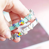 A silver and a green faux leather buckle bracelet with sparkly heart, sparkly butterfly, enamel coloured flower, shiny crown, shiny heart and sparkly LOVE charms. Suitable for both children and adults.