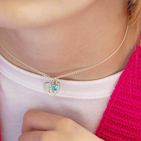 Model wears Child's Initial Heart and Birthstone Necklace with the initial "K" and March birthstone.