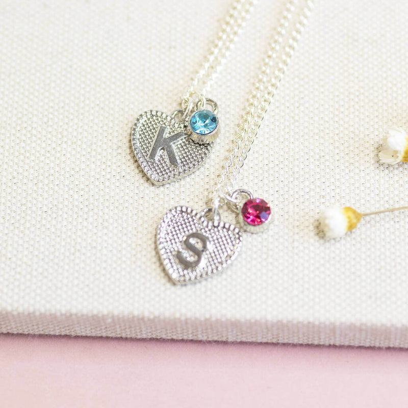 Image shows two Child's Initial Heart and Birthstone Necklaces with "K" initial and March birthstone and "S" initial with October Rose Birthstone.