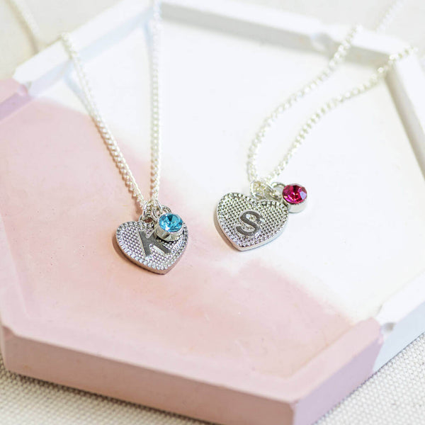 Image shows two Child's Initial Heart and Birthstone Necklaces with "K" initial and March birthstone and "S" initial with October Rose Birthstone.