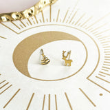 image shows a pair of christmas tree and reindeer stud earrings on a gold and white background