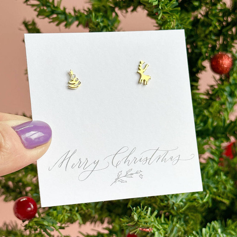 Image shows mini christmas tree and reindeer earrings on a merry christmas sentiment card