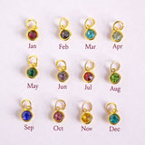 Twelve gold-toned monthly charm jump rings arranged in a 3-by-4 grid on a white background, each with a different colored faceted gemstone and labeled Jan through Dec below.