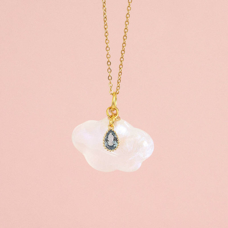 Image shows Cloud and Raindrop Necklace on a pink backdrop.