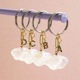 Image shows four Cloud Keyring with Rainbow Initials on a peach backdrop.