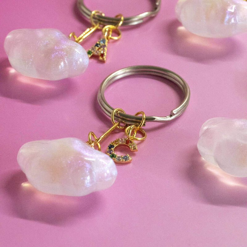Image shows four Cloud Keyring with Rainbow Initials on a pink backdrop.
