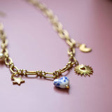 Custom charm necklace with gold plated links featuring heart, star and porcelain charms on pink background