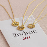 Image shows three Crystal Zodiac Coin Necklaces on the 'in the Zodiac by JOY" booklet.