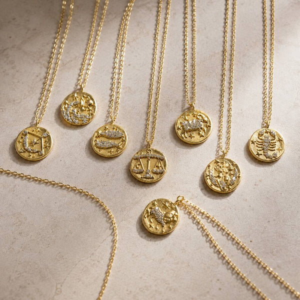 Collection of gold zodiac coin necklaces with crystal details, celestial jewellery trend for layering
