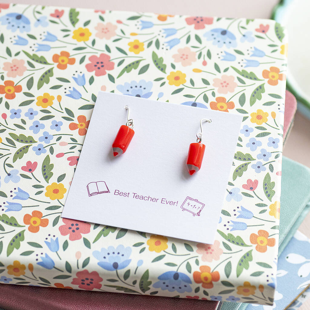 Red pencil drop earrings on a floral gift display, colourful statement jewellery with silver hooks.