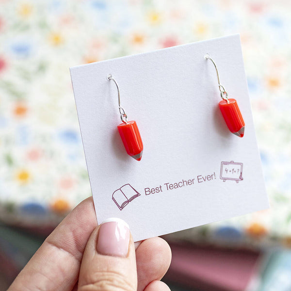 Red pencil drop earrings with silver hooks on a keepsake card, colourful novelty jewellery for everyday wear.