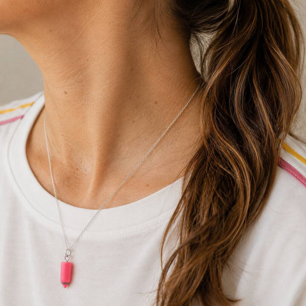 Pink pencil charm necklace on a silver chain, colourful novelty jewellery for everyday layering and styling.