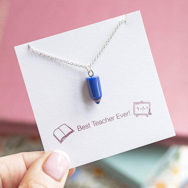 Blue pencil charm attached to a silver necklace chain displayed on a Best Teacher Ever sentiment card.
