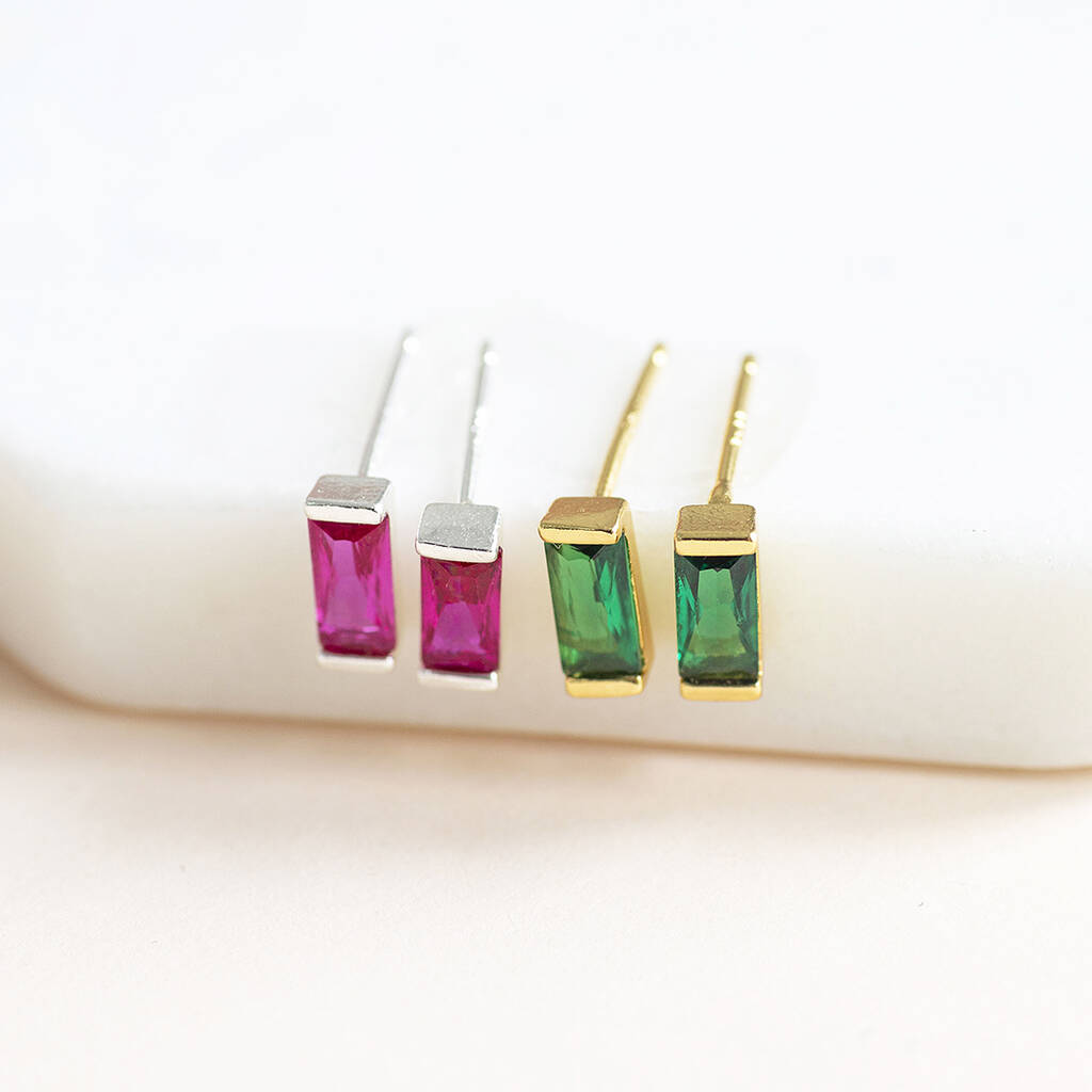 Dainty baguette birthstone studs with vivid pink and green stones in silver and gold tones for colourful ear styling.
