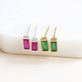 Dainty baguette birthstone studs with vivid pink and green stones in silver and gold tones for colourful ear styling.
