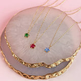 Image shows three birthstone star necklaces oin a marble trinket dish