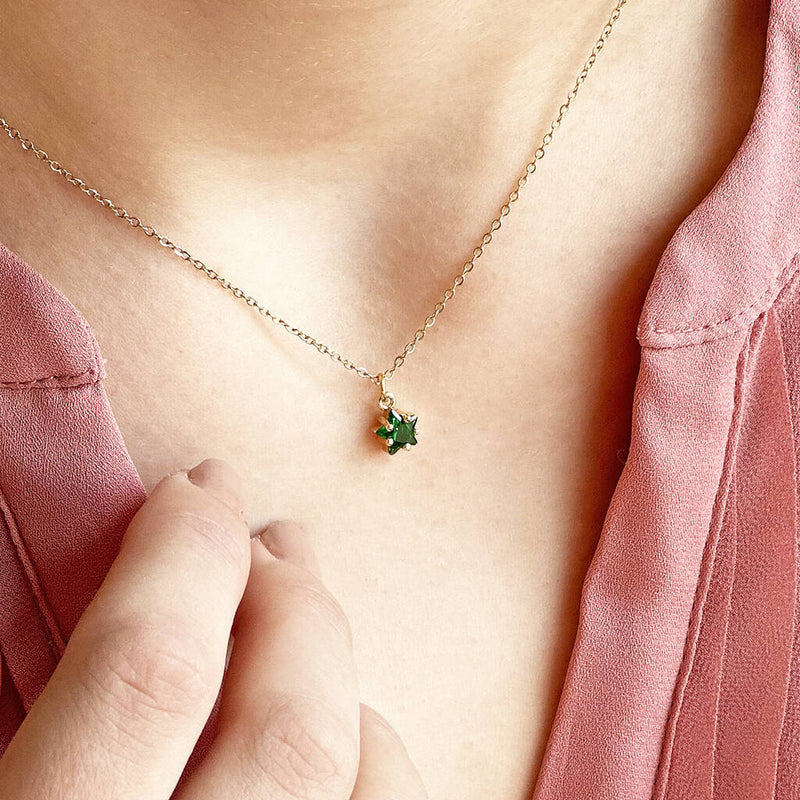 Image shows a model wearing an emerald May birthstone dainty star necklace